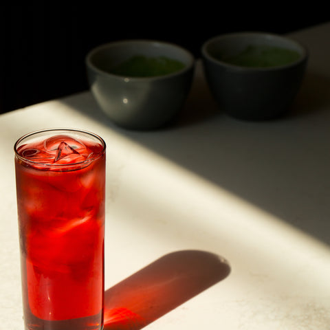 glass-with-iced-red-beverage-reflects-on-a-white-table